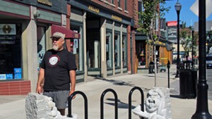 Calais sculptor Chris Miller on Main Street with the sculptural bike rack he created