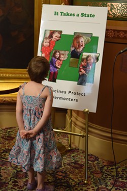 Mia Hockett's daughter, Merin, looks at a poster that a group of Vermont mothers, including hers, put together to emphasize the importance of immunizations. - TERRI HALLENBECK