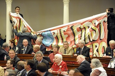 Protesters, led by the Vermont Workers' Center, hang a banner at Gov. Peter Shumlin's inauguration in January. - FILE: JEB WALLACE BRODEUR
