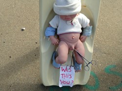 Protesters used a plastic doll as a prop Monday. - MOLLY WALSH/SEVEN DAYS