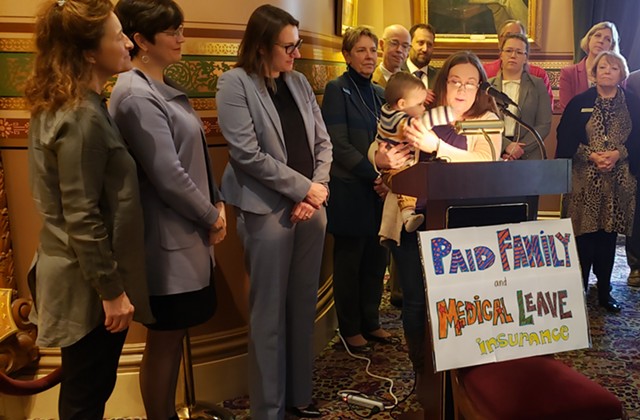 Christine Vance holding her son, Ben, as she addresses supporters of paid family leave in the Statehouse on Wednesday - KEVIN MCCALLUM
