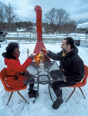 Marlena Tucker-Fishman and Noah Fishman enjoying drinks by Zenbarn's outdoor wood-burning stove - JEB WALLACE-BRODEUR