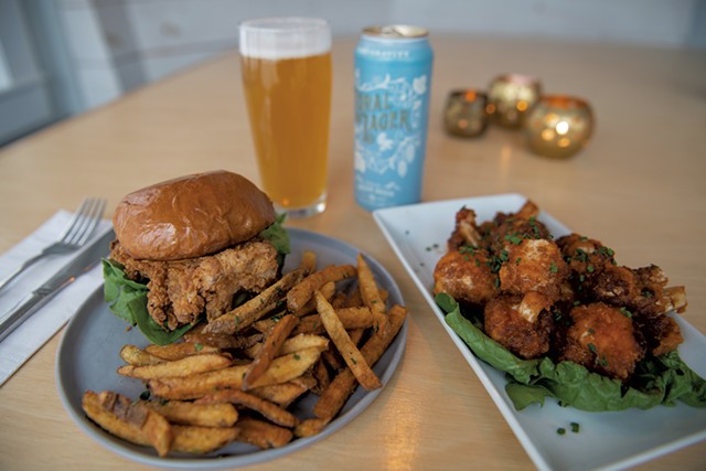 Crispy chicken sandwich with herb fries, cauliflower wings in a housemade maple barbecue sauce, and a Loral Lager by Zero Gravity - DARIA BISHOP