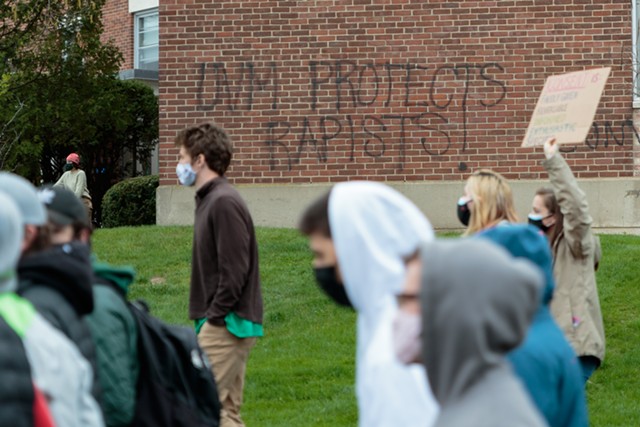 Students march past graffiti criticizing UVM - COLIN FLANDERS ©️ SEVEN DAYS