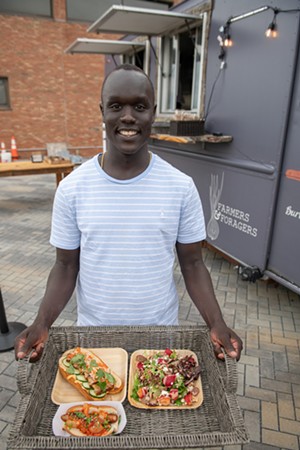 Deng Adiang carrying a tray of freshly prepared food: a kimchi hot dog, a pork belly b&aacute;nh m&igrave; and a strawberry salad - DARIA BISHOP