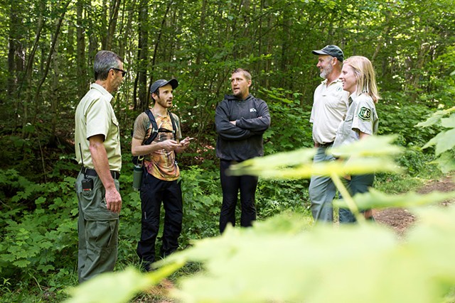 U.S. Forest Service employees talk with participants at the Rainbow Family gathering. - CALEB KENNA