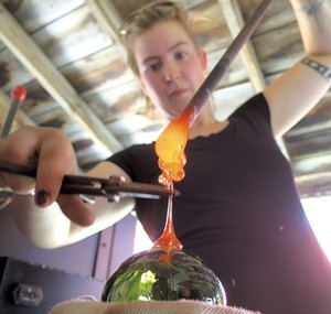 Glassblower Camille Ames putting the finishing touches on an ornament - MATTHEW THORSON