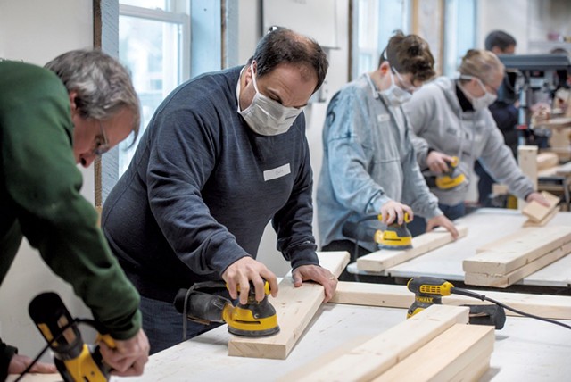 Volunteers sand wood boards before building begins - GLENN RUSSELL