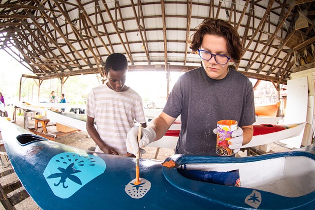 Basil Hopkinson (right) stenciling fireflies on their kayak, with the help of fellow camper Jonathan Kafumbe - CAT CUTILLO