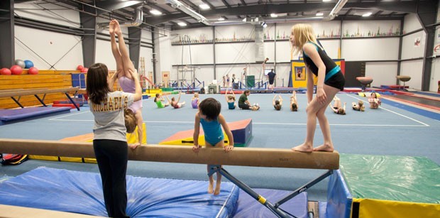 Balance beam coach Rebecca Belrose helps gymnasts with their moves