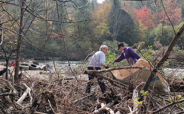 Volunteers wrestling with debris on the banks of the Winooski River in Plainfield - ALANA NORWAY