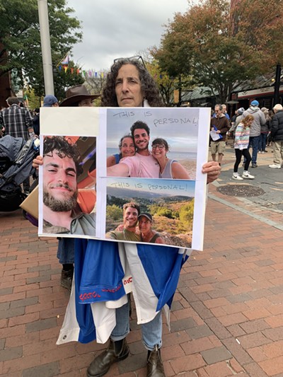 Naomi Barell holding a poster with photos of her son, who is currently serving in the IDF - HANNAH FEUER ©️ SEVEN DAYS