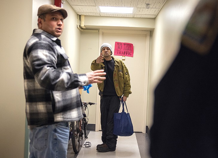 Resident manager Mayank Nauriyal (left) and a security guard talking to a man in a hallway - JAMES BUCK