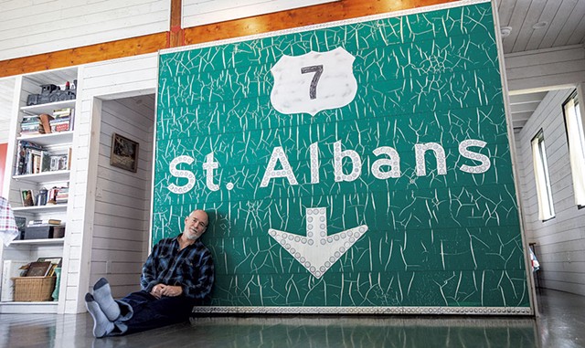 Paul Hance in front of a St. Albans exit sign on the first floor of his summer home - OWEN LEAVEY