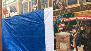A tarp covers the vandalized section of the "Everyone Loves a Parade!" mural in Burlington.