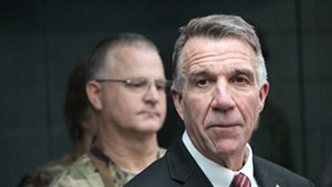 Maj. Gen. Steven Cray (background) looks on as Gov. Phil Scott addresses the media