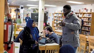 Yuol Herjok of Spectrum Youth &amp; Family Services (right) speaking with Burlington High School senior Halima Said at the school's Spectrum Multicultural Help Desk