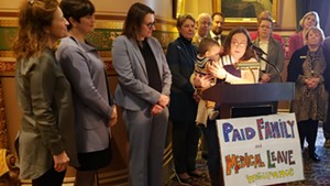 Christine Vance holding her son, Ben, as she addresses supporters of paid family leave in the Statehouse on Wednesday