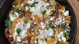 Shakshuka of tomatoes, yellow pepper and radish greens with poached eggs