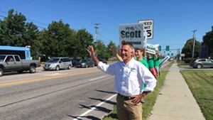 Phil Scott waves to passersby on Shelburne Road in South Burlington on Monday.